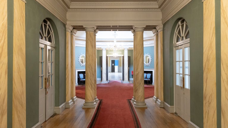 A view down the main corridor inside Bath Assembly Rooms covered in a red carpet.